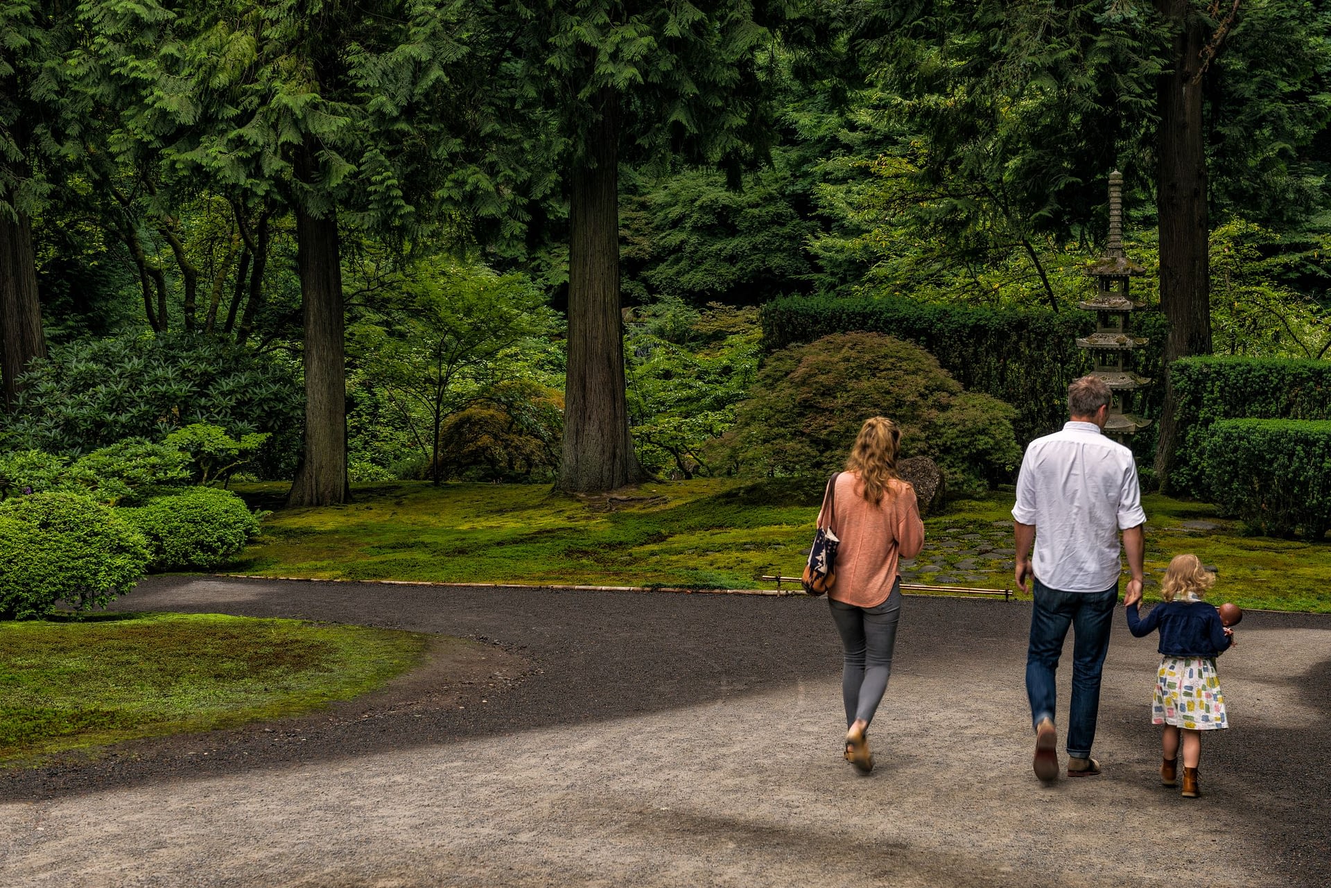 A family consisting of a mother, father, and toddler walks through the Portland Japanese Garden