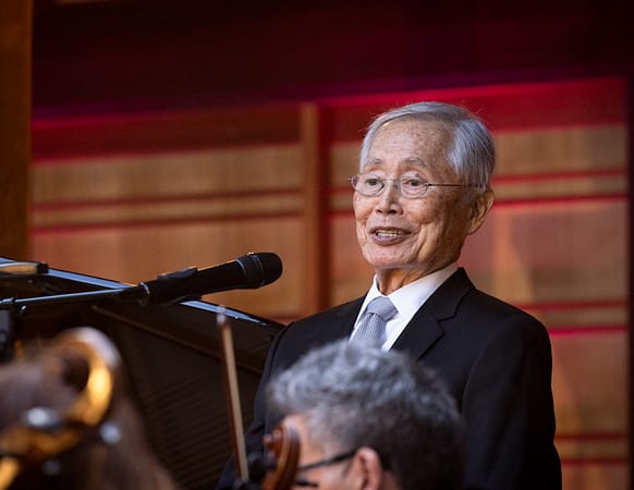 A man leans back while speaking into a mic
