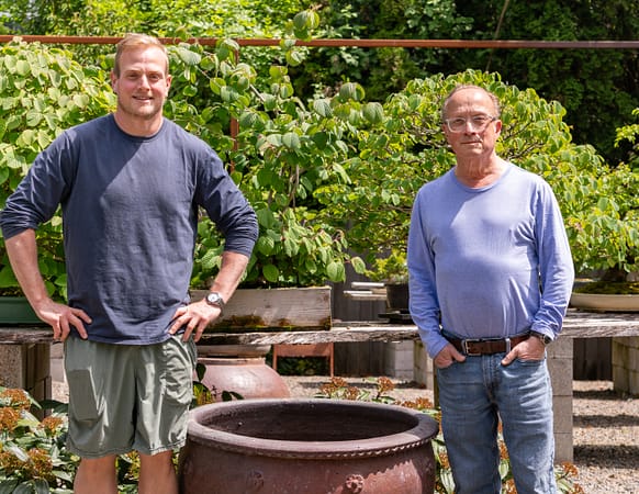 two men standing next to a large pot