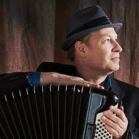 Portrait of a Caucasian man in a fedora hat holding an accordion