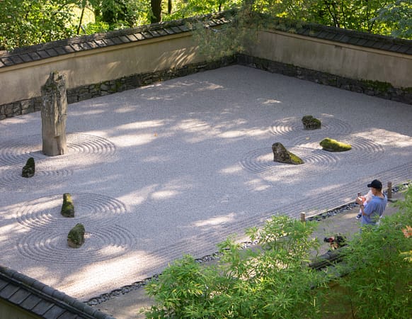 A father holds his child taking a photo of a raked gravel garden