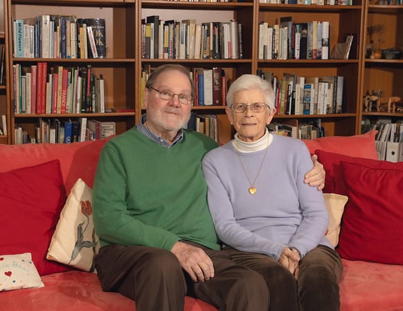 a married couple, man and woman, sitting on a couch in a library