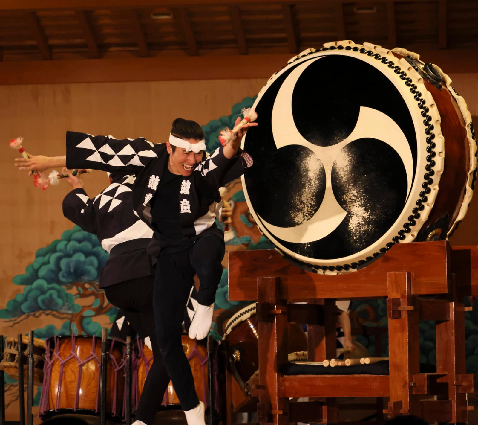 a man plays a taiko drum with a smile