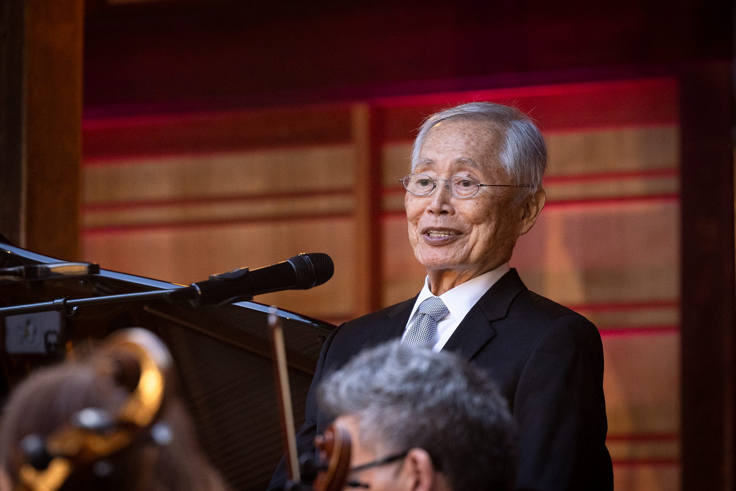A man leans back while speaking into a mic