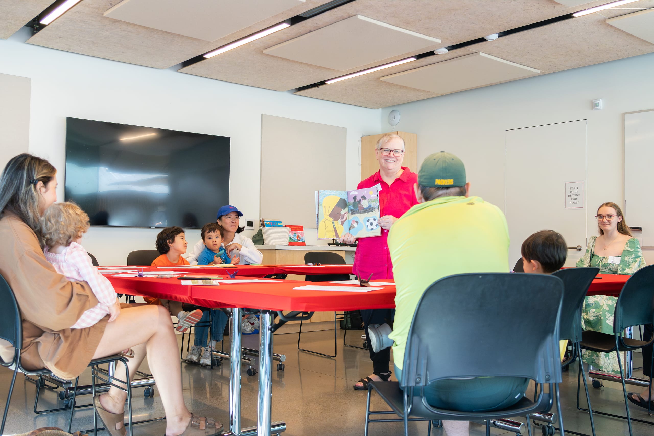 A woman reading a book to children in a classroom.