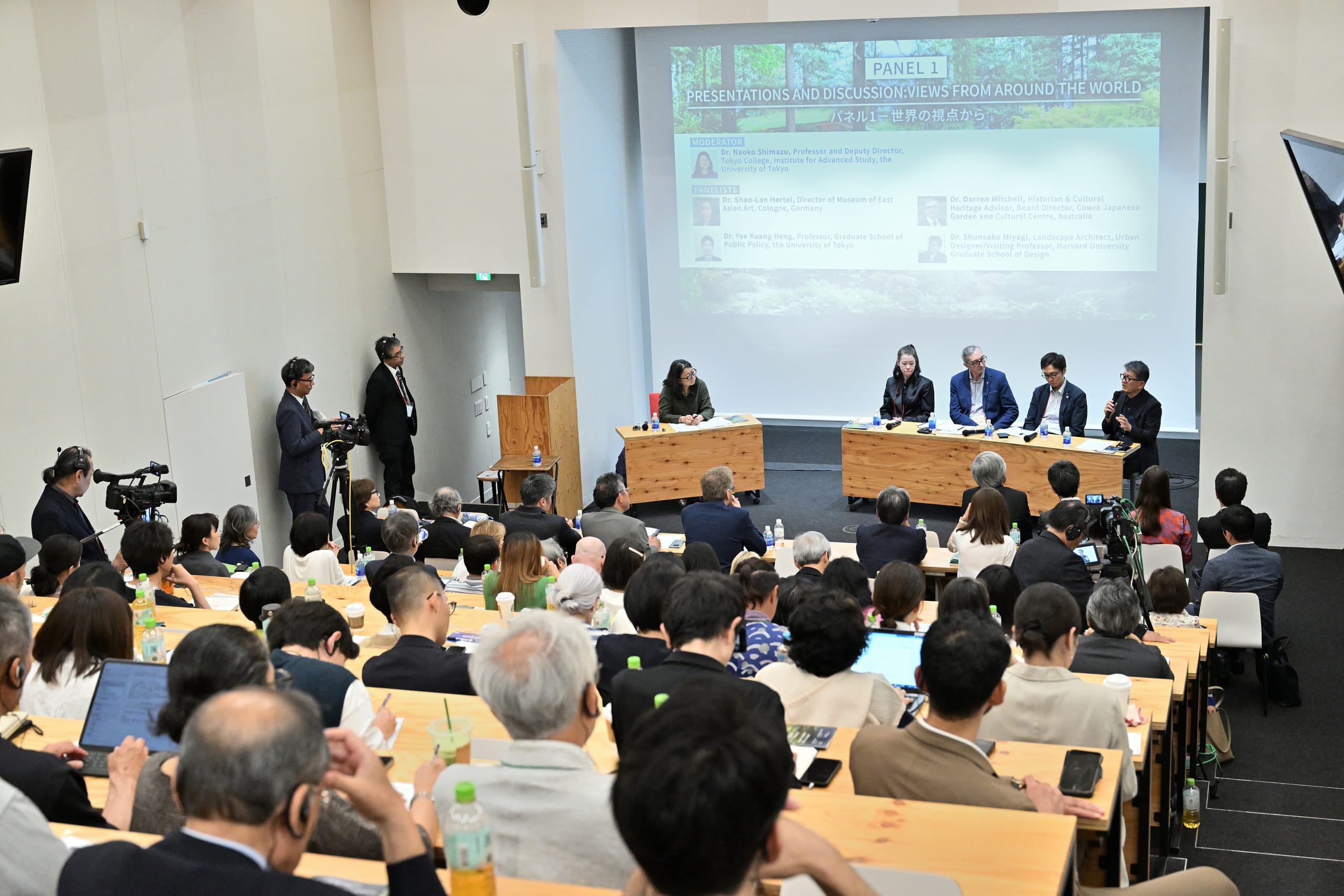 a lecture room with a crowd watching a panel discussion