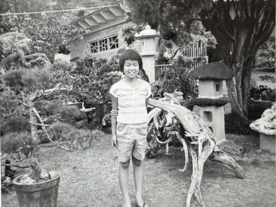a young girl in a garden with a Japanese stone lantern, black and white