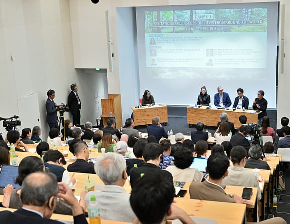 a lecture room with a crowd watching a panel discussion