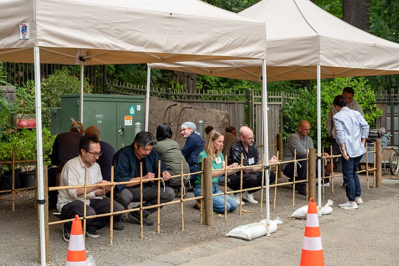 a group of people working next to unfinished bamboo fences