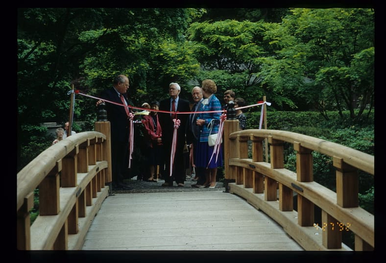 People cutting the ribbon in a ceremony of the opening of a new wooden bridge in Portland Japanese Garden.