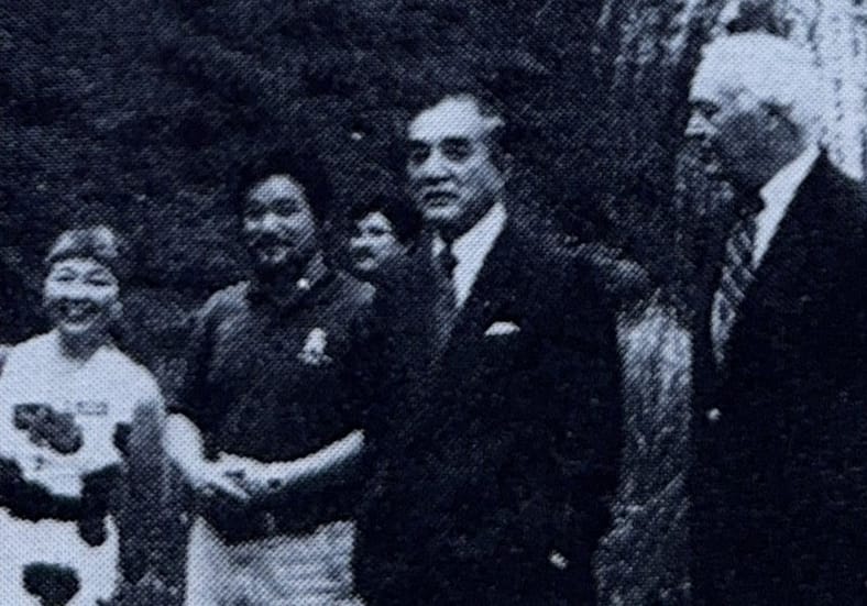 A grainy black and white photo of four people standing.