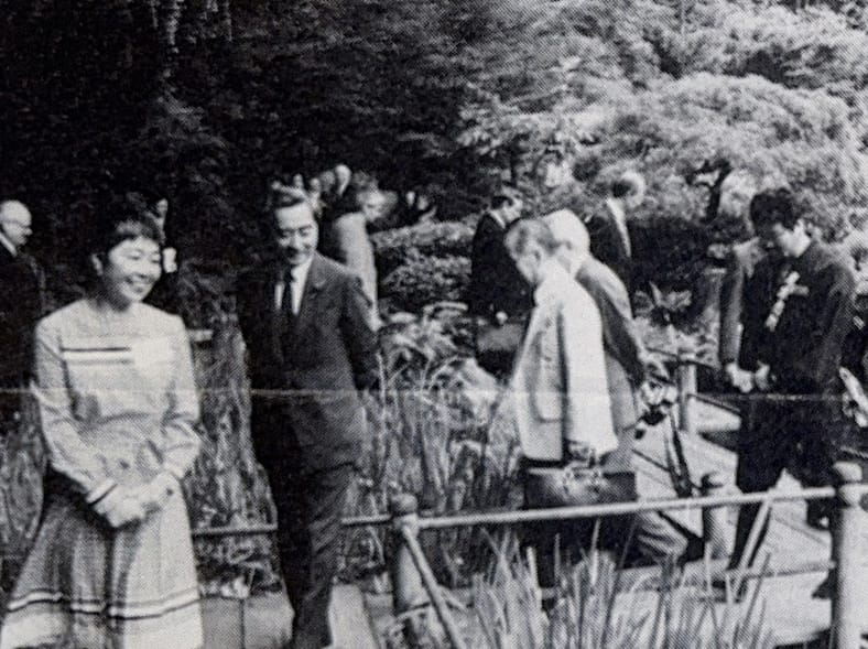 a black and white image of a group of people walking on a bridge during a tour