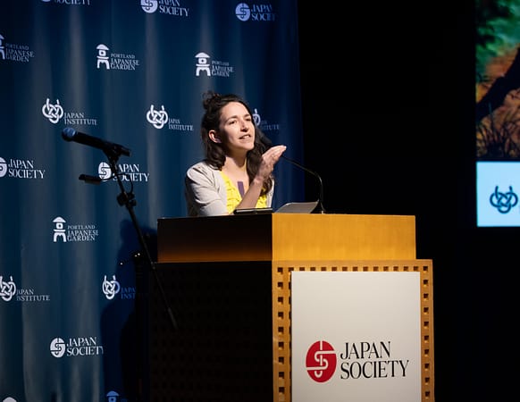Nomi Stone reading a poem at a podium.
