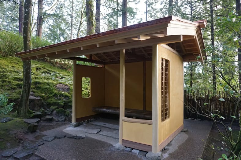 A wooden, sheltered structure with a bench inside but only 3 walls so that people sitting inside can see the garden around them better.