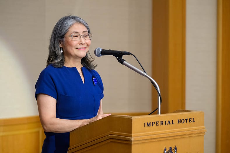 a woman standing at a podium smiling