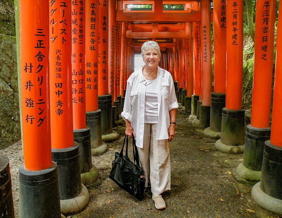 a woman standing next to bright red wooden posts