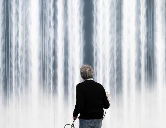 A man has his back to the camera, as he works on a large painting.