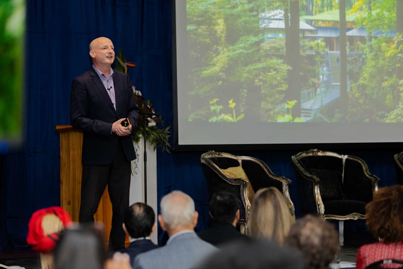 Steve Bloom standing on a stage speaking to attendees of a peace symposium in Cape Town, South Africa.