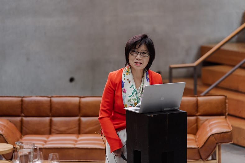 Yuko Hasegawa standing a podium giving a presentation.
