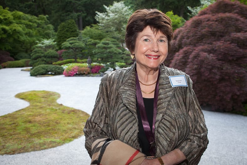 a woman smiling in front of a raked gravel garden