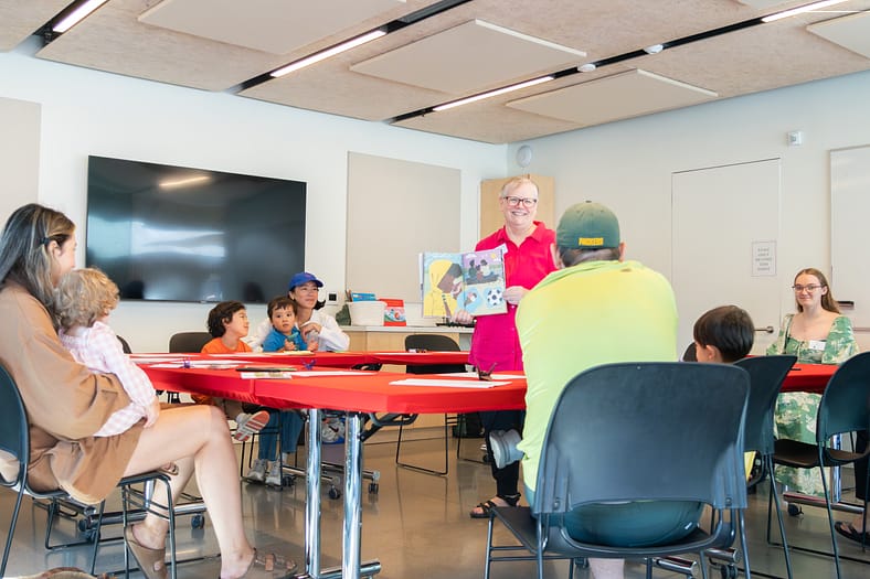 A woman reading a book to children in a classroom.