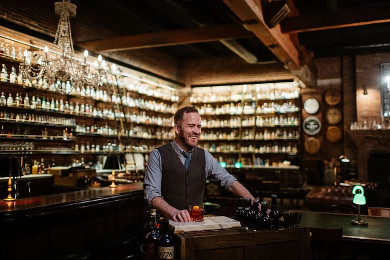 Bartender in a whiskey library serving a drink.
