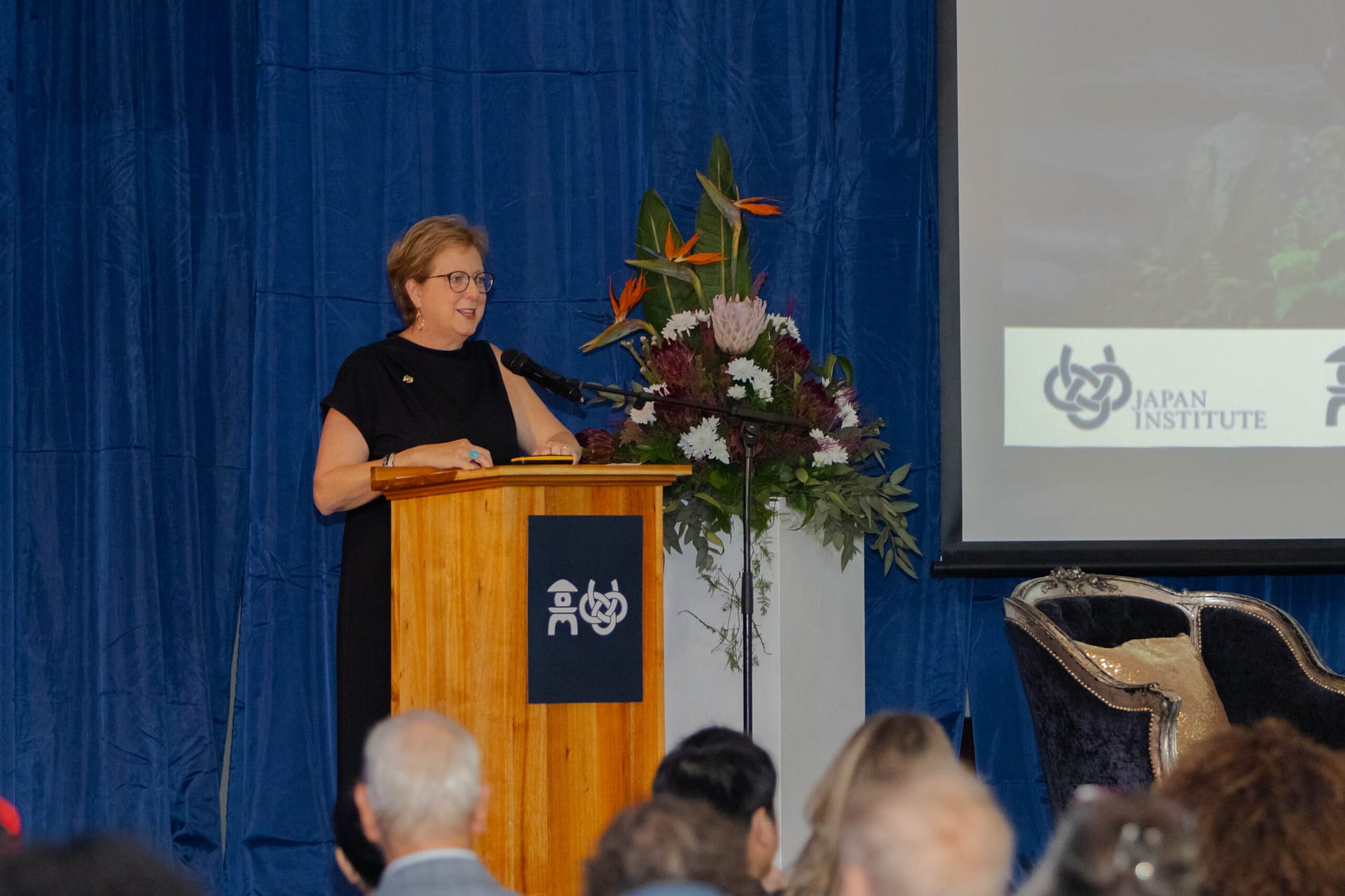 Caryl Stern standing at a podium in front of a seated audience.
