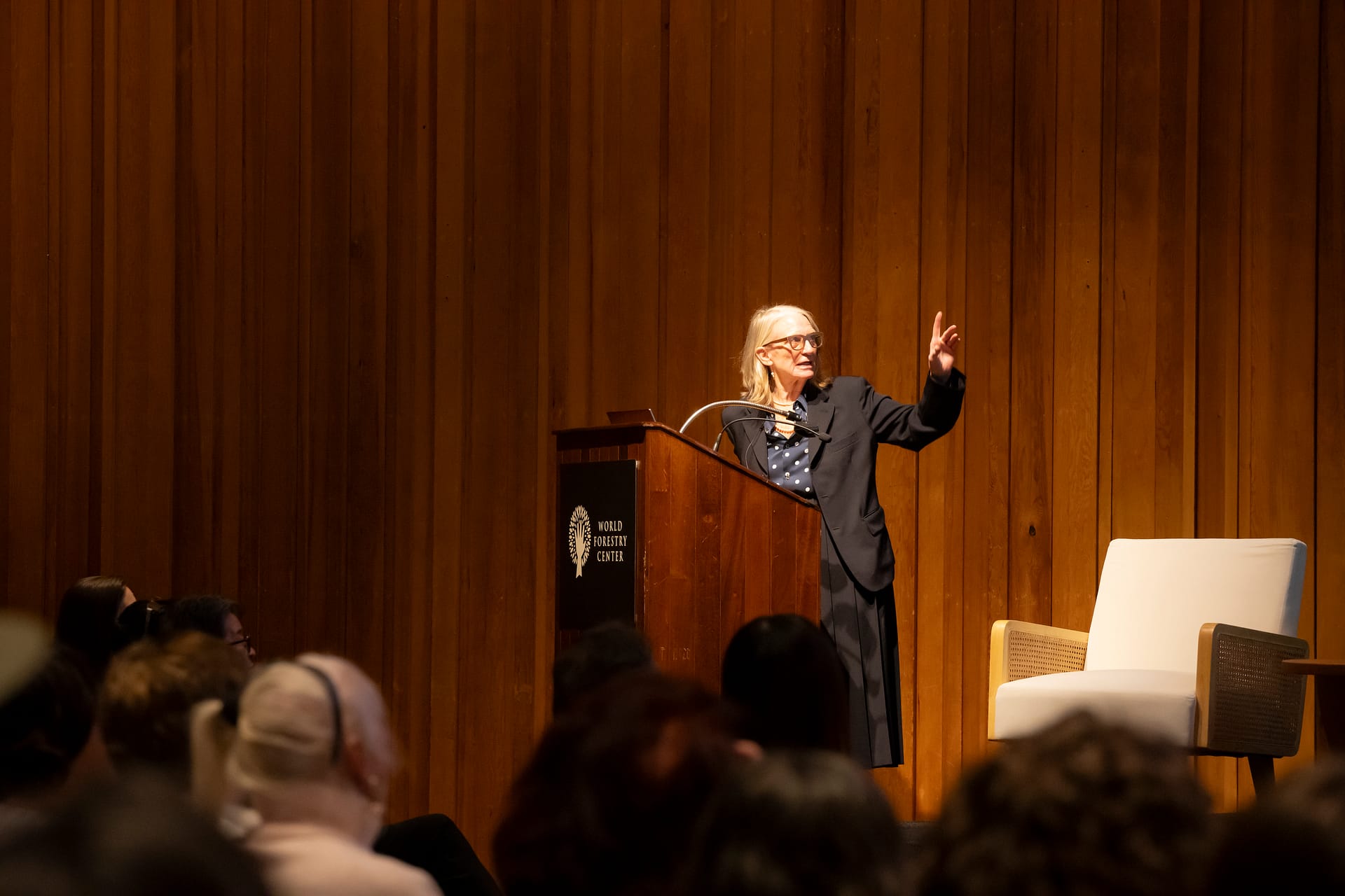 A woman speaking behind a podium to a seated audience.