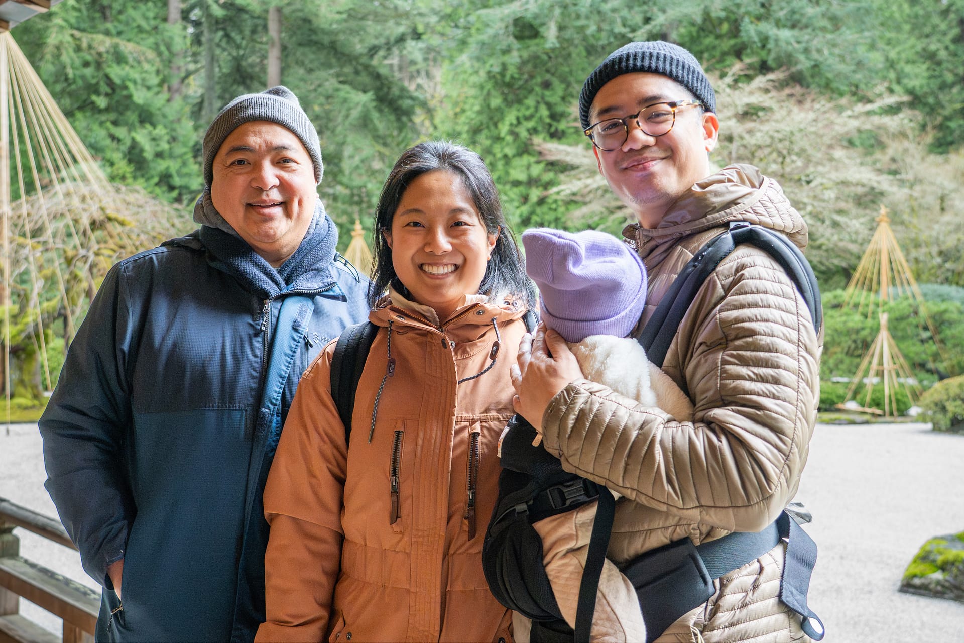 A couple and their baby pose next to an older family member.