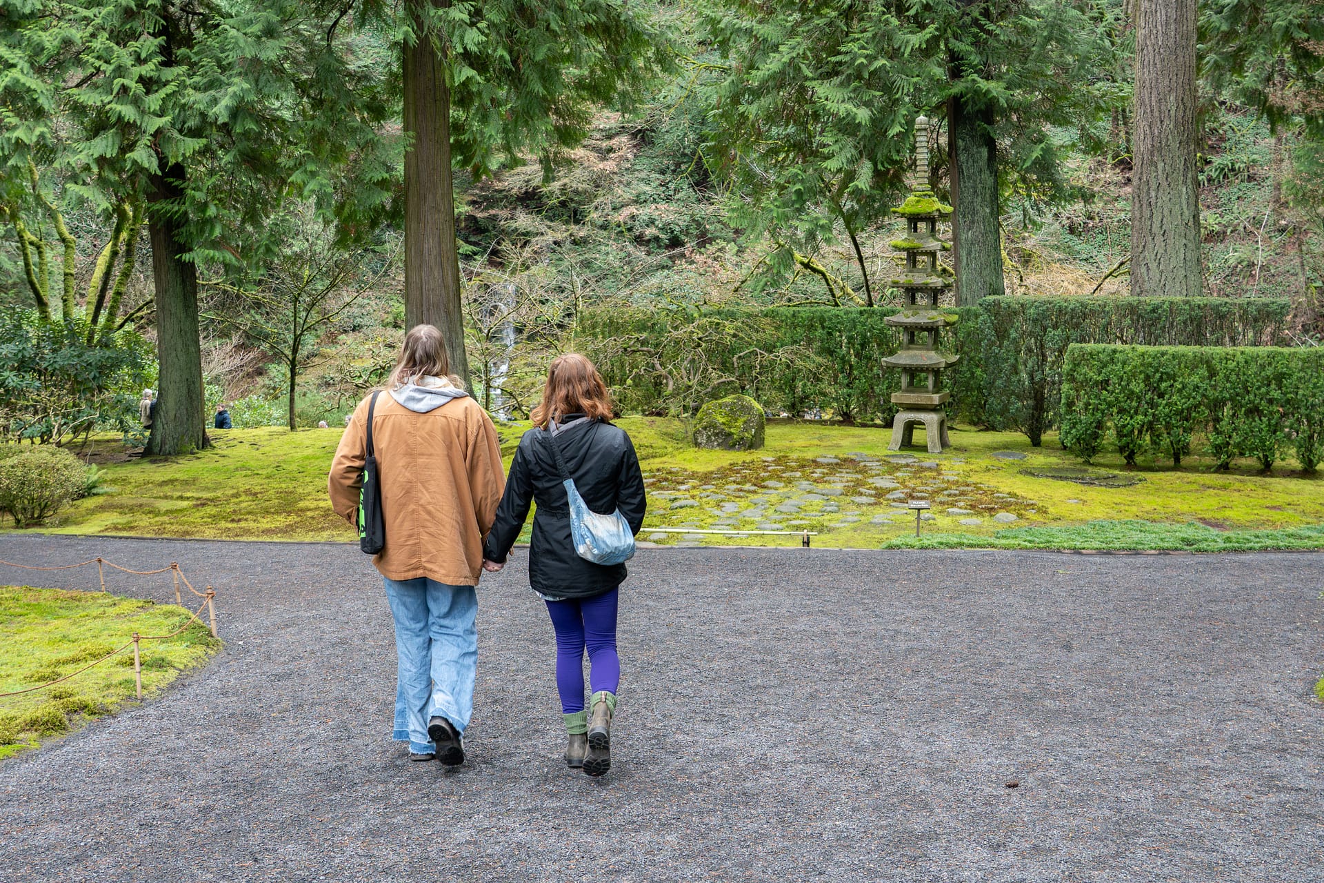 a couple holding hands, walking on a gravel path