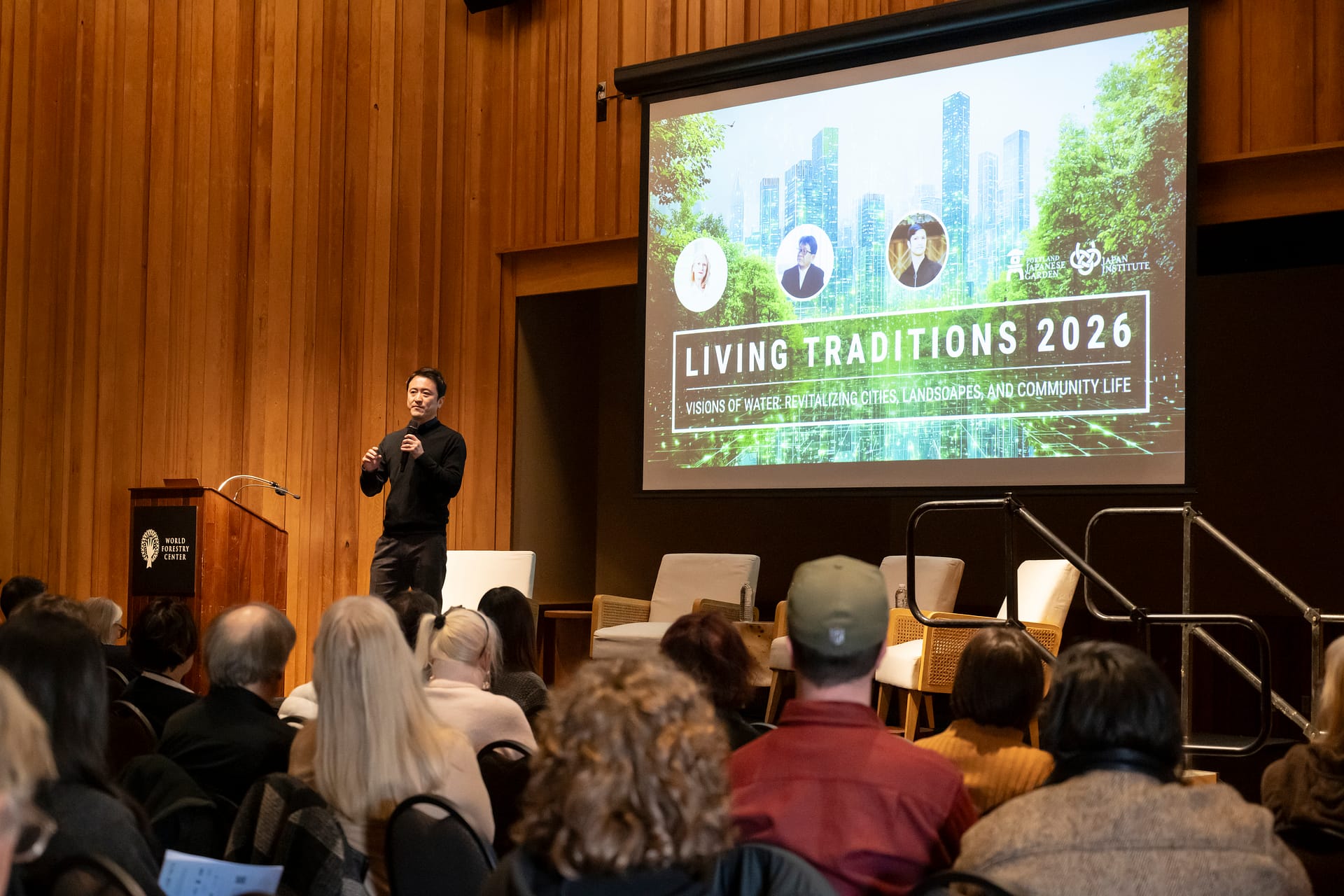 a man holding a microphone talking to a seat audience