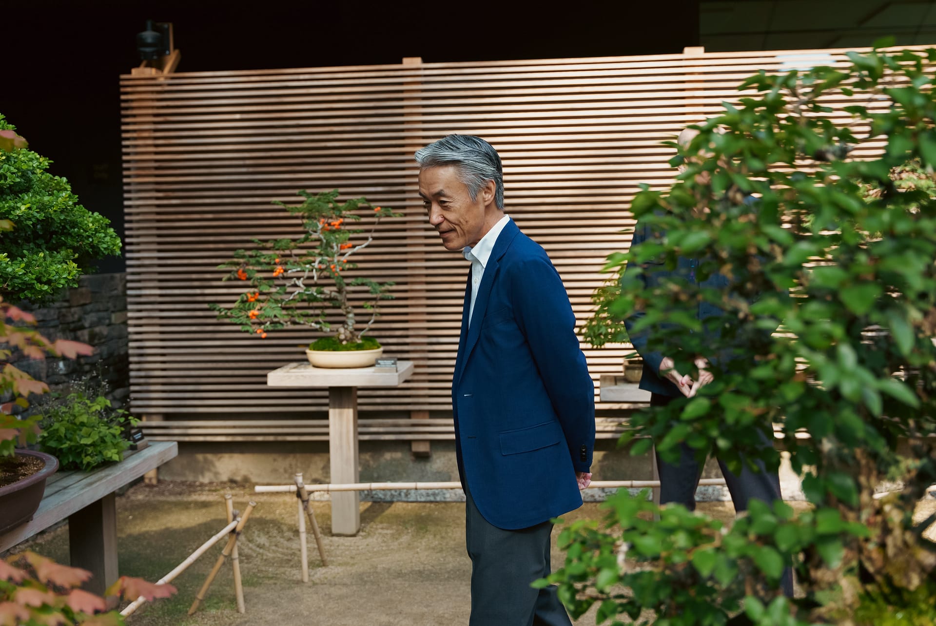Ambassador Shigeo Yamada looks at bonsai on a terrace at Portland Japanese Garden.