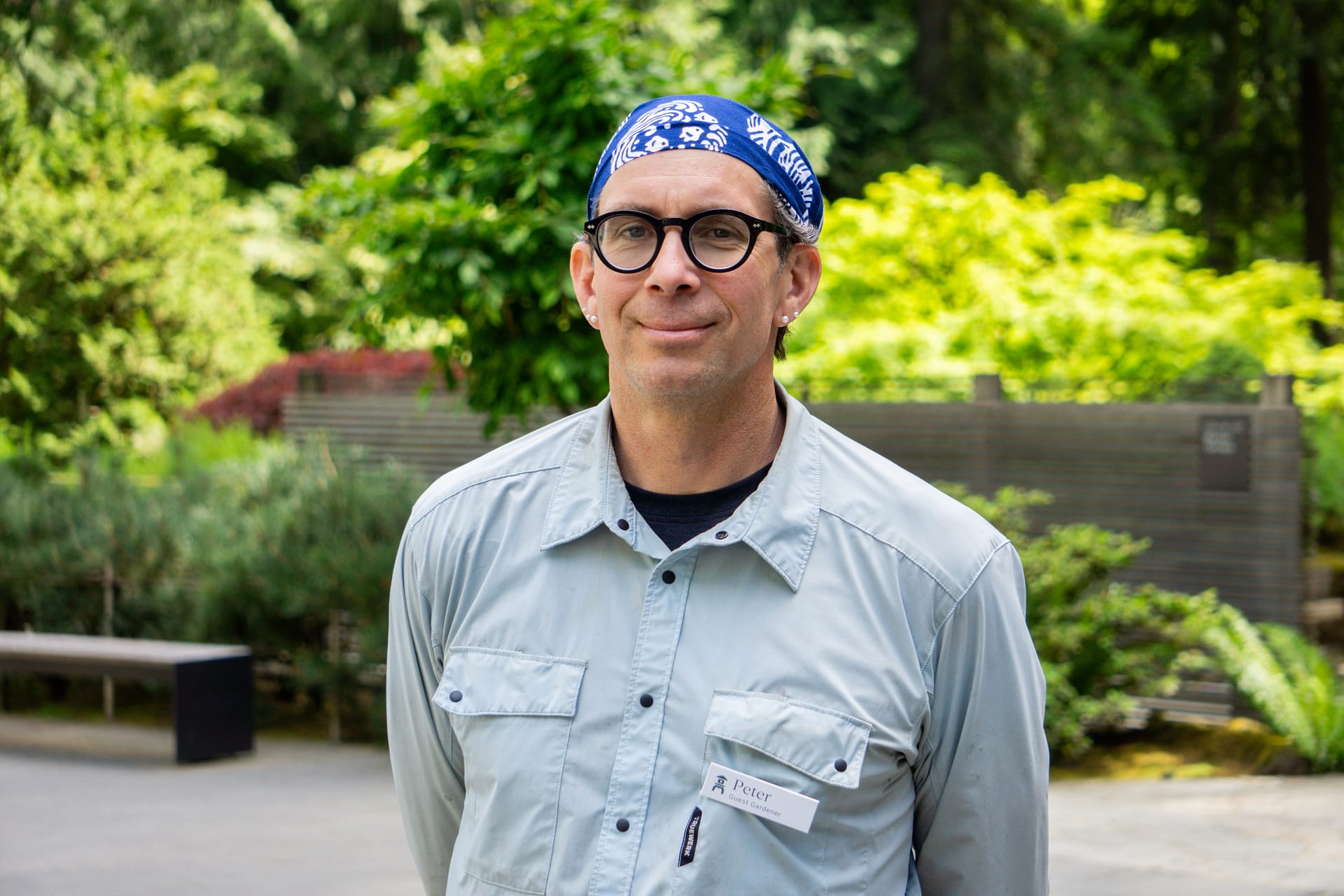 portrait of a gardener wearing a headband, round glasses, and a button up shirt