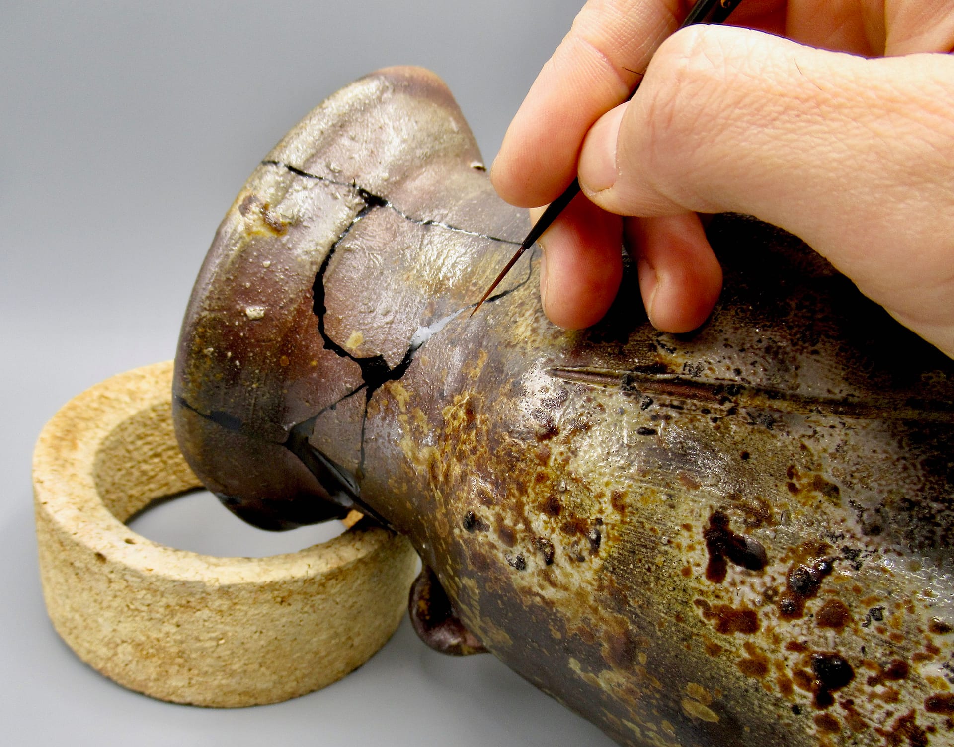 a close up view of a broken ceramic vase being repaired with lacquer