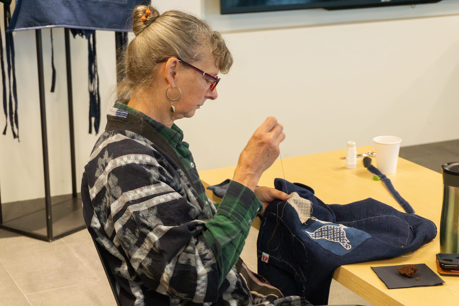 A woman embroiders a denim apron.