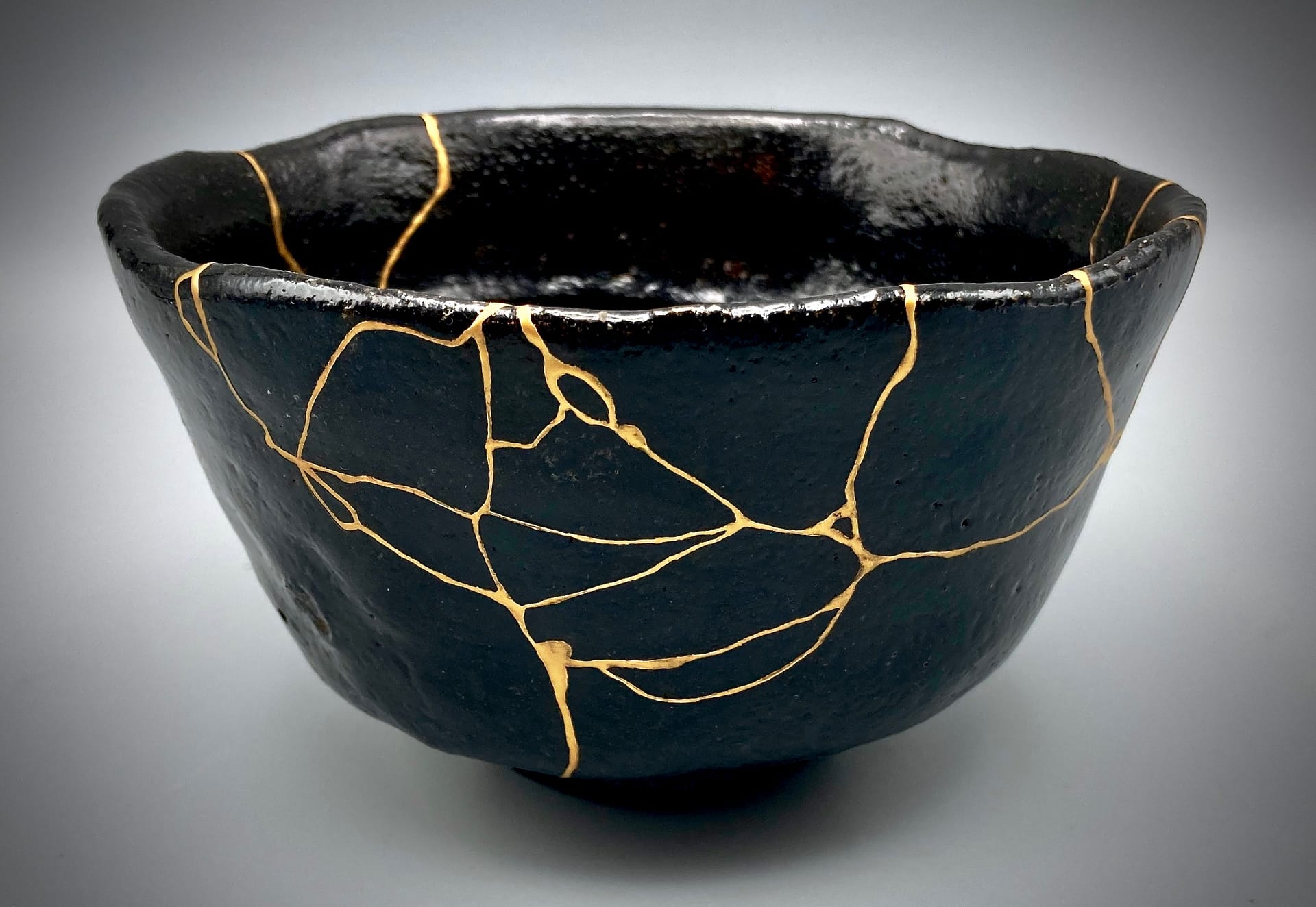 a black cup with cracks repaired with gold