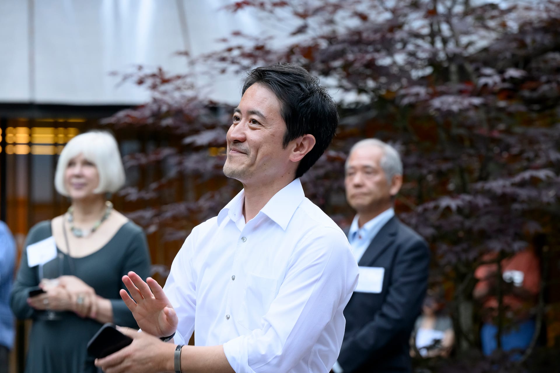 Aki Nakanishi applauds a speaker giving remarks while attending a Portland Japanese Garden event.