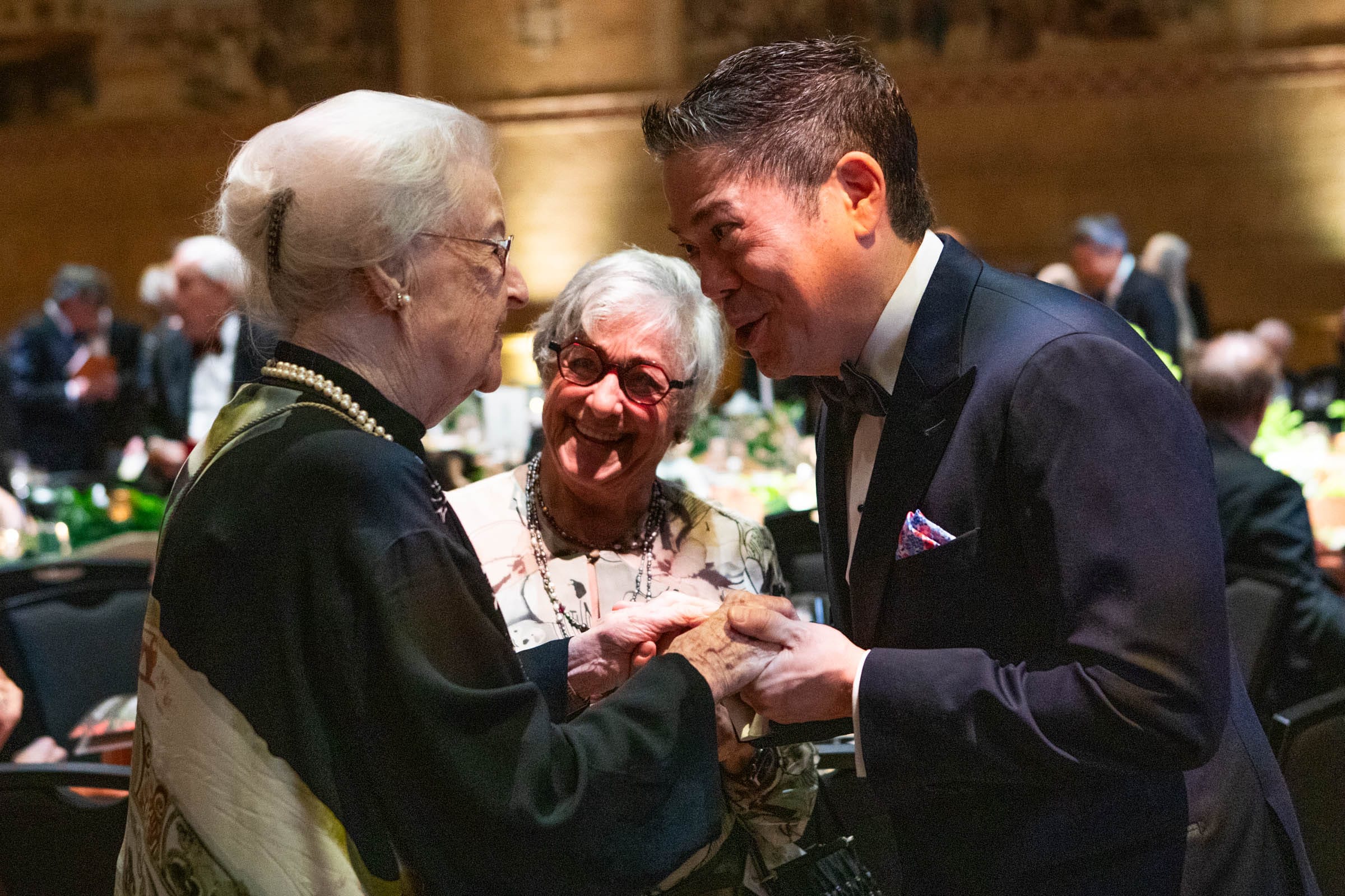 Maggie Drake and Board Trustee Douge de Weese greeting each other in front of another woman at a gala.