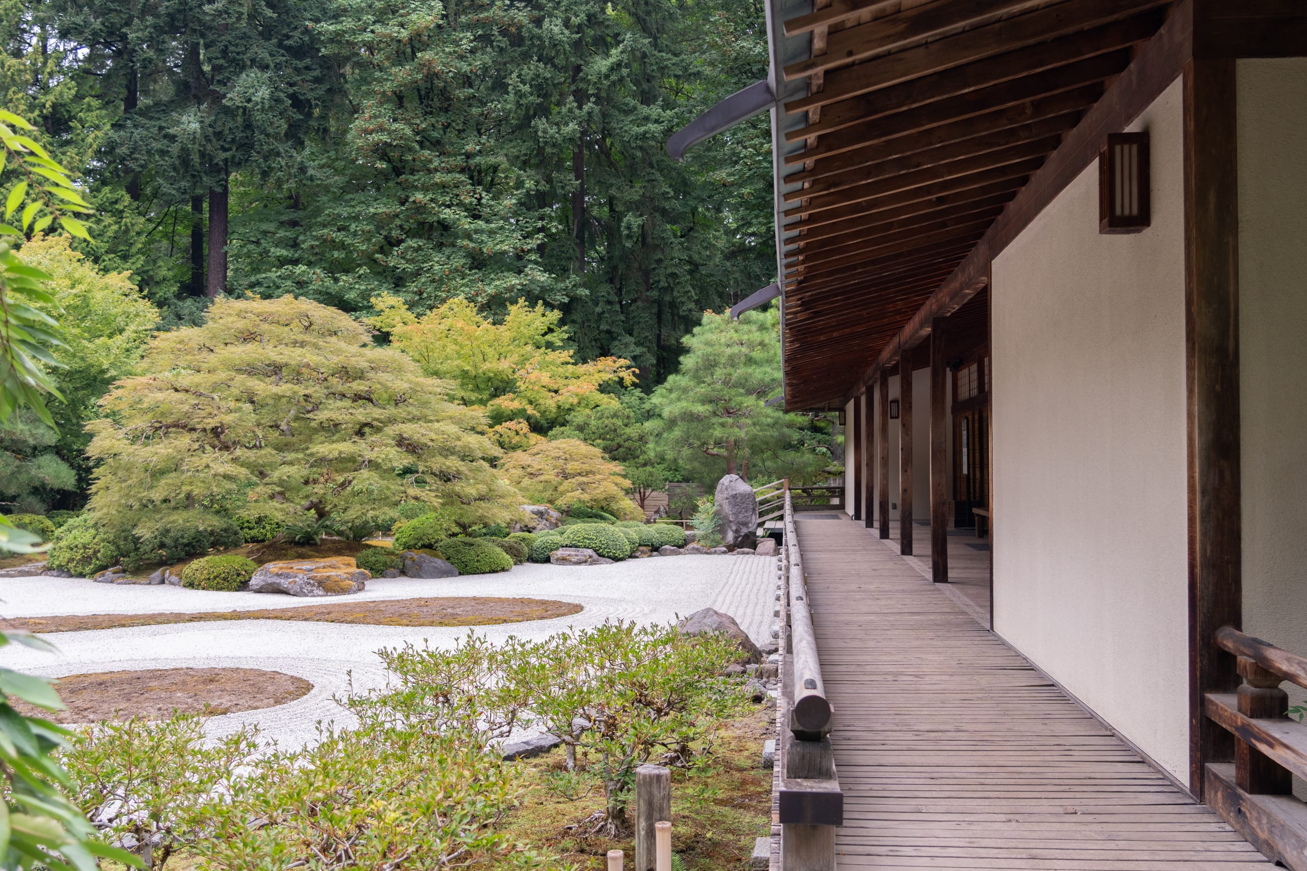 a deck of a building next to raked gravel and a maple