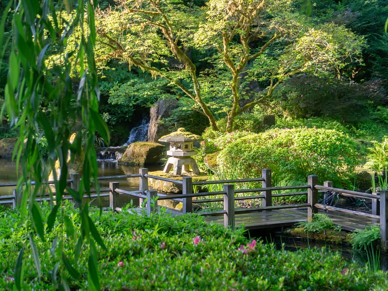 a stone lantern near a wooden bridge