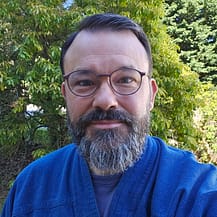 Portrait of Mark Bourne in font of green foliage.