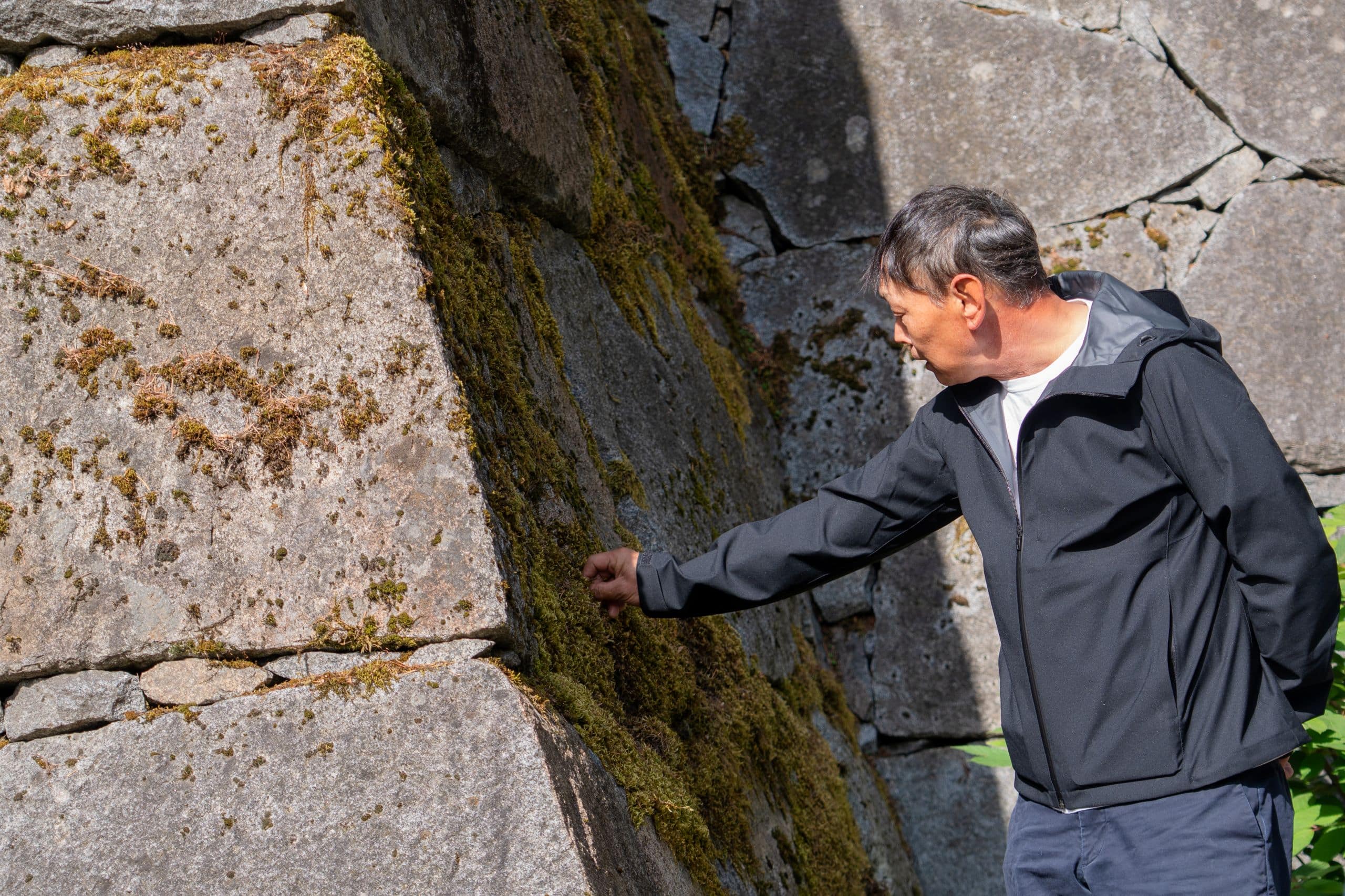 a man touches a stone in a large castle wall