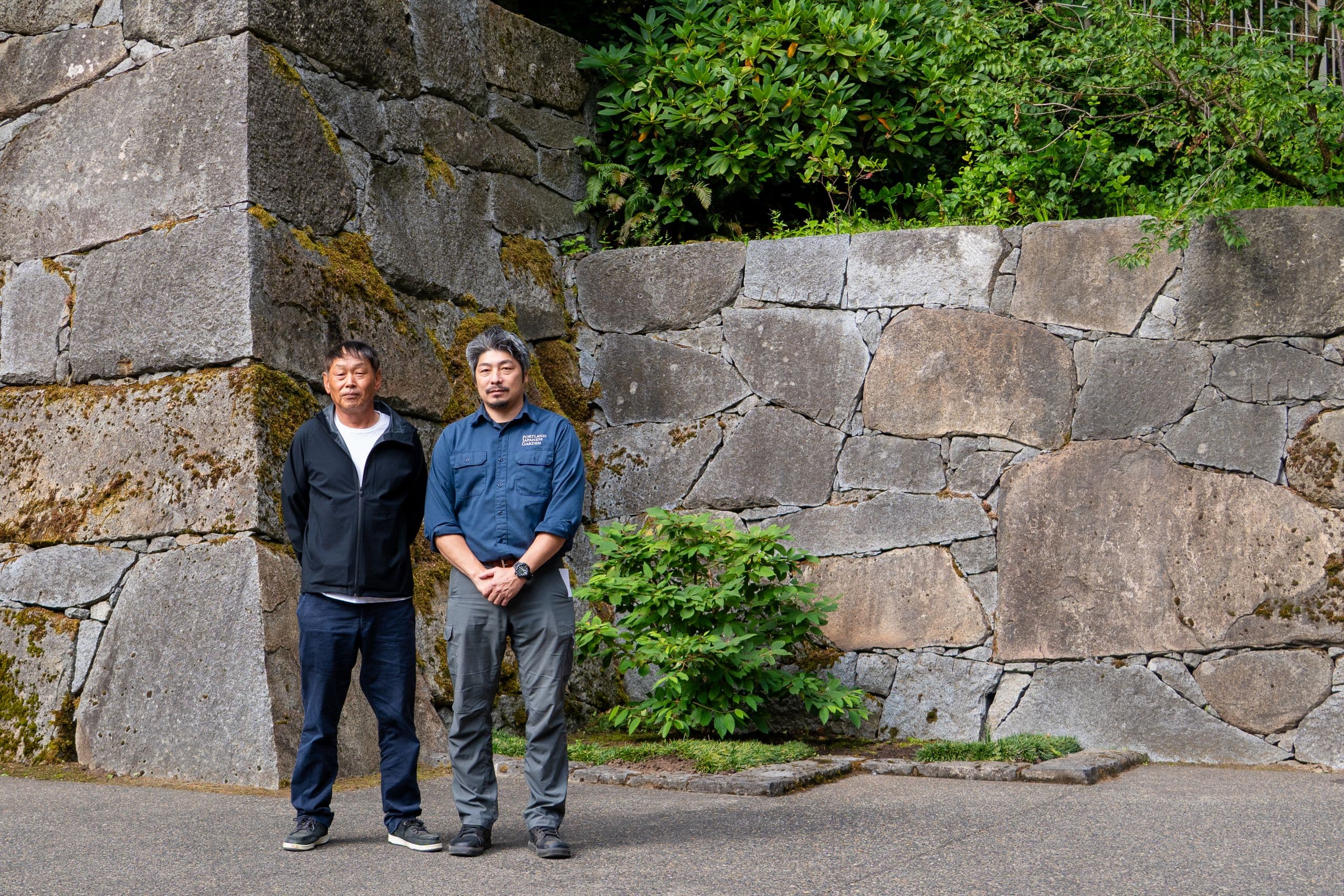 two people standing in front of a large castle wall