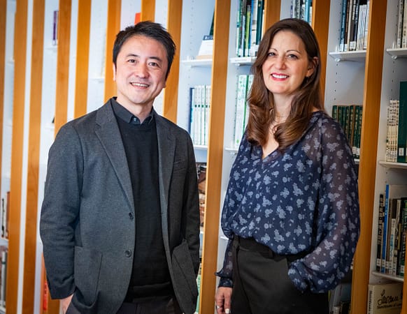 two people standing and smiling in front of a book shelf in a library