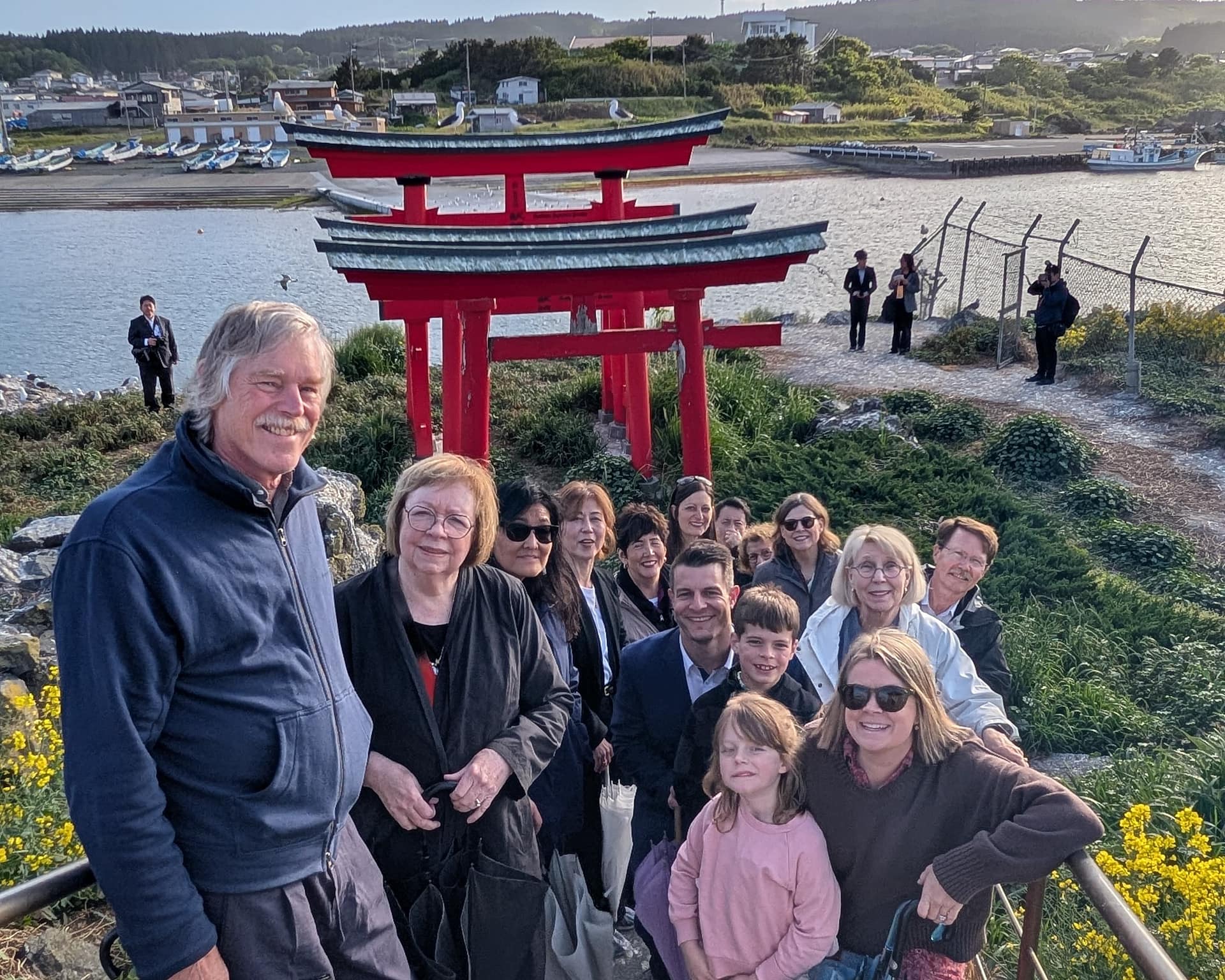 a group of people smiling with bright red torii gates in the background