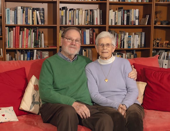 a married couple, man and woman, sitting on a couch in a library