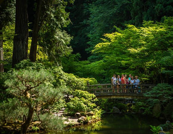 A fair away shot of people smiling and standing on a wooden bridge.