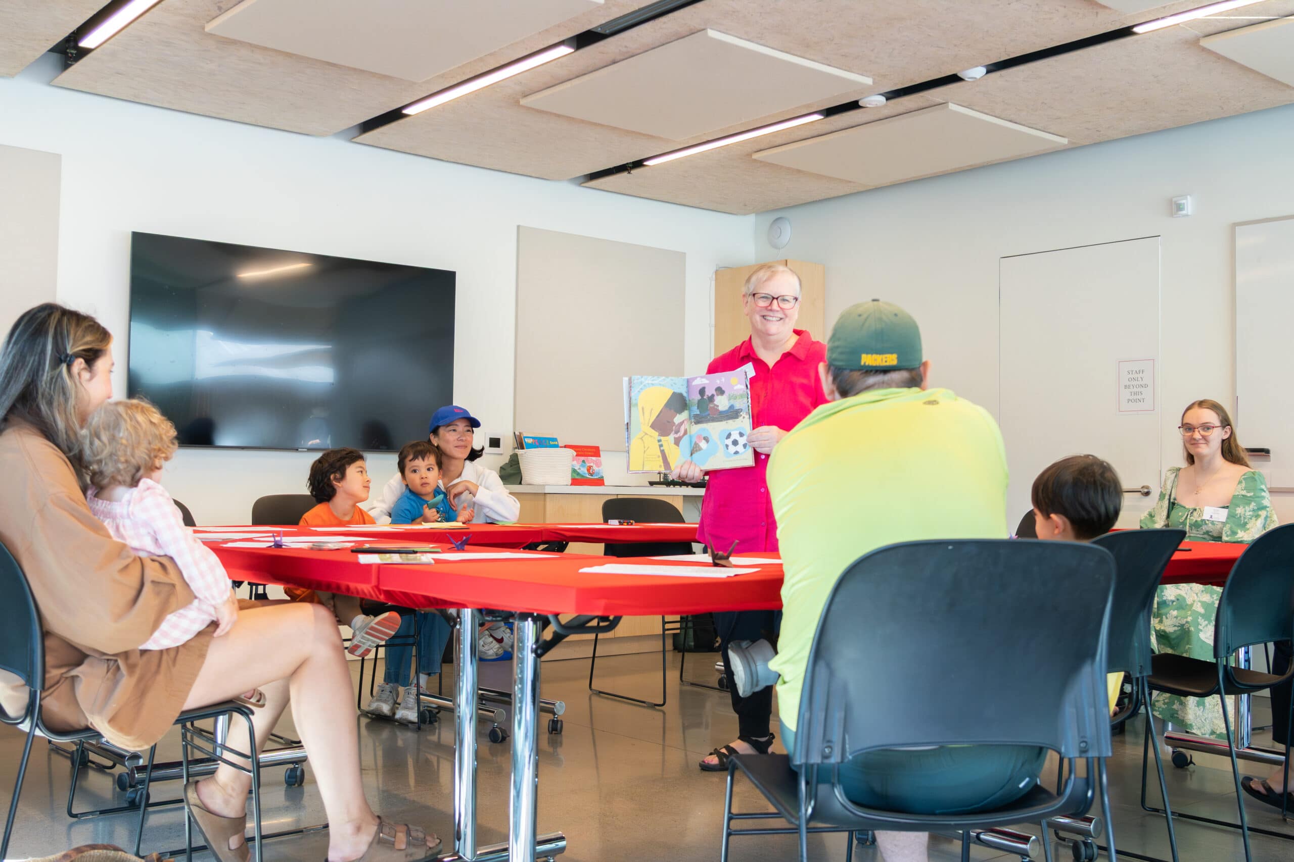 A woman reading a book to children in a classroom.
