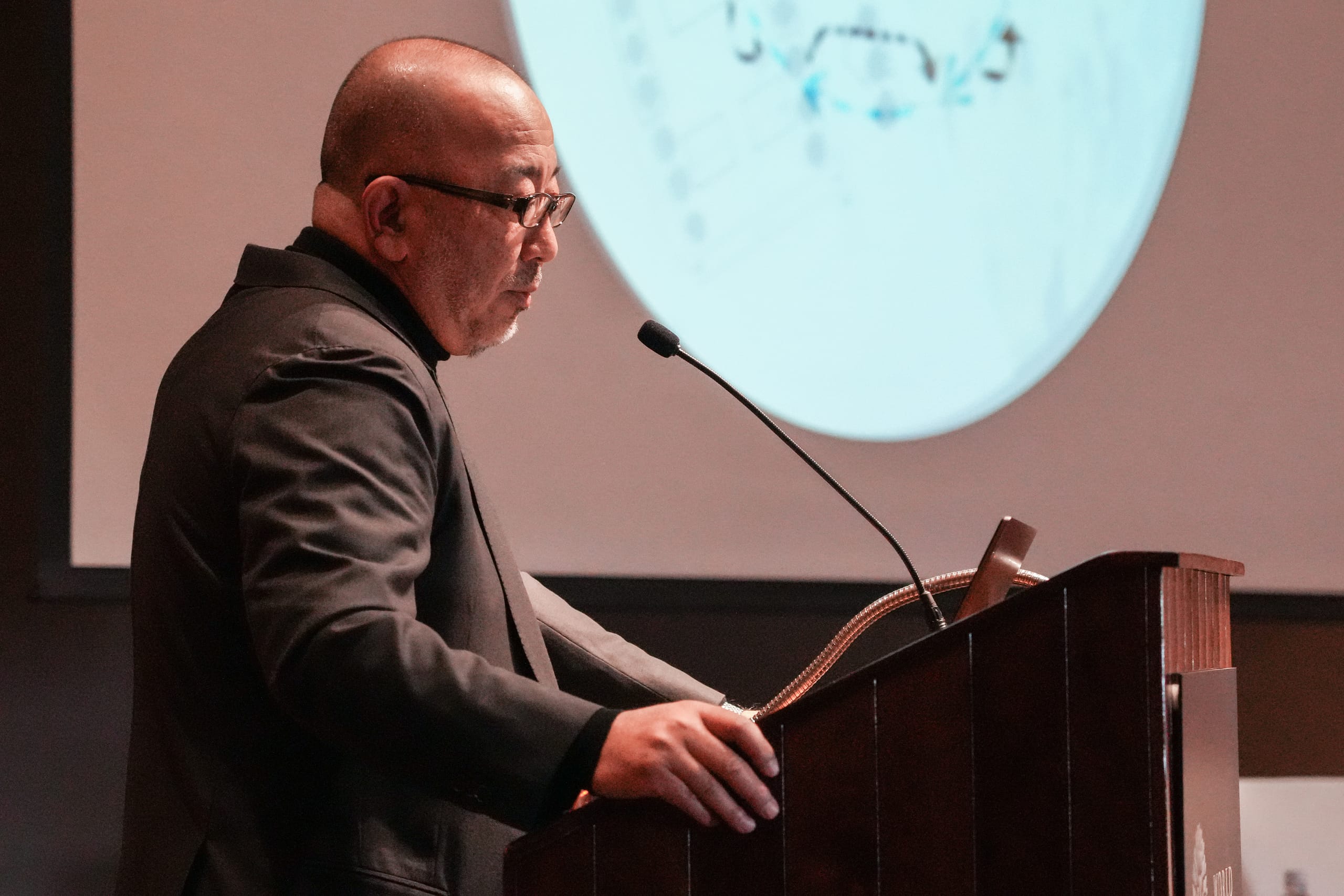 A man speaks into a microphone at a podium.