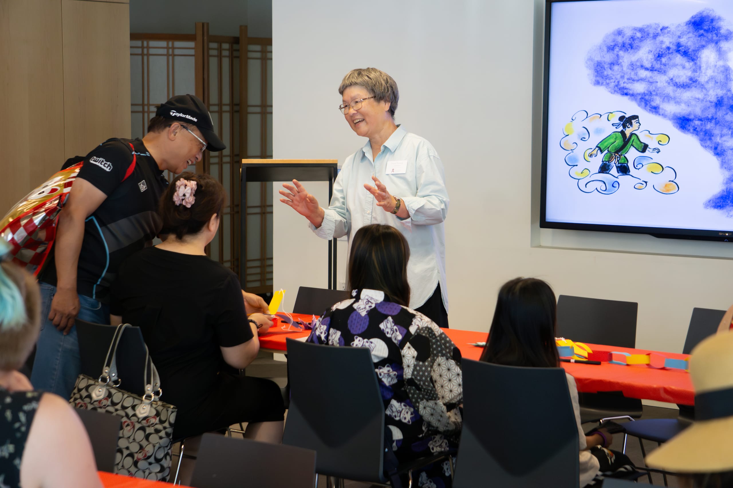 a woman smiling while teaching people about tanabata festival